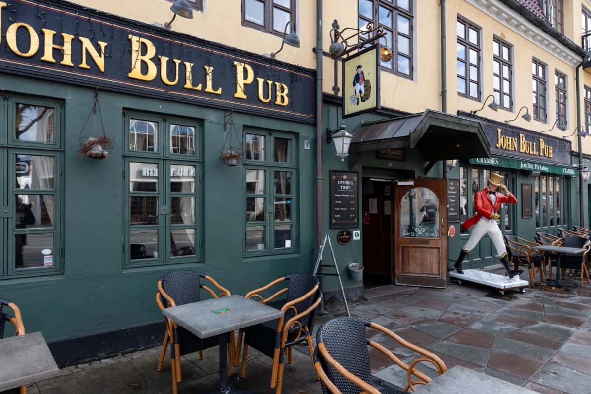 Terrasse et façade d'un pub dans une rue pavée de la vieille ville d'Aalborg, au Danemark