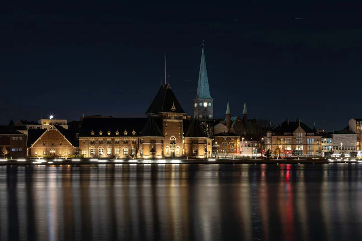 Front de mer d'Aarhus la nuit, avec la flèche de la cathédrale et l'ancienne douane se reflétant dans le port, Jutland, Danemark