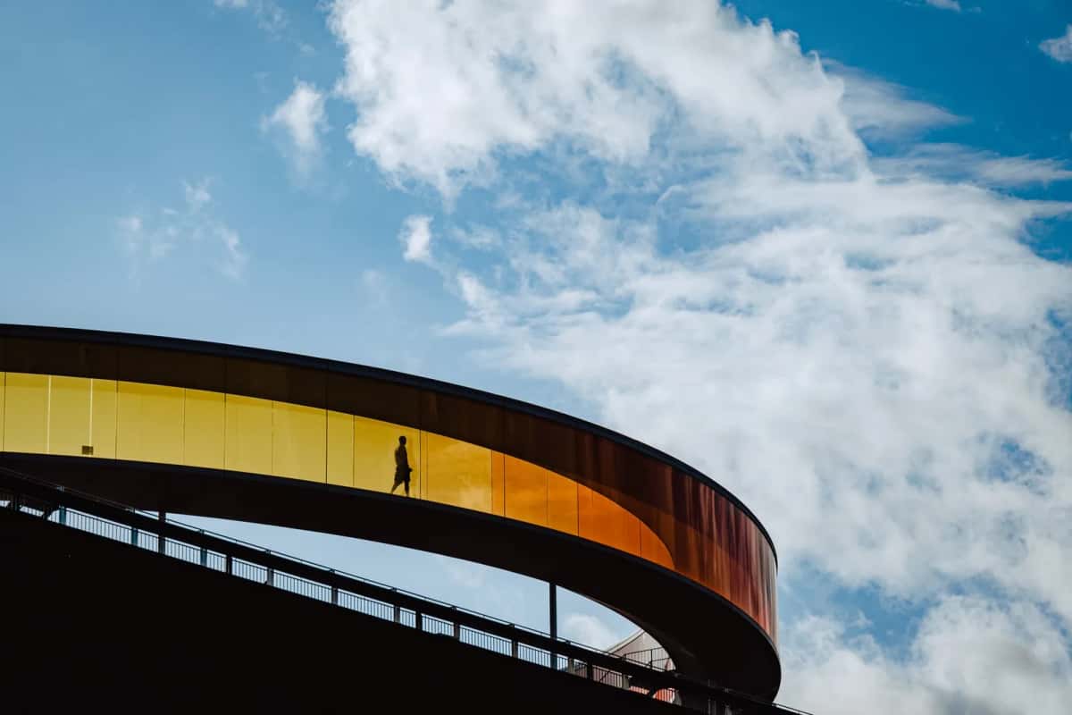 Passerelle circulaire en verre teinté du Your Rainbow Panorama, sur le toit de l'ARoS à Aarhus, silhouette d'un visiteur à contre-jour