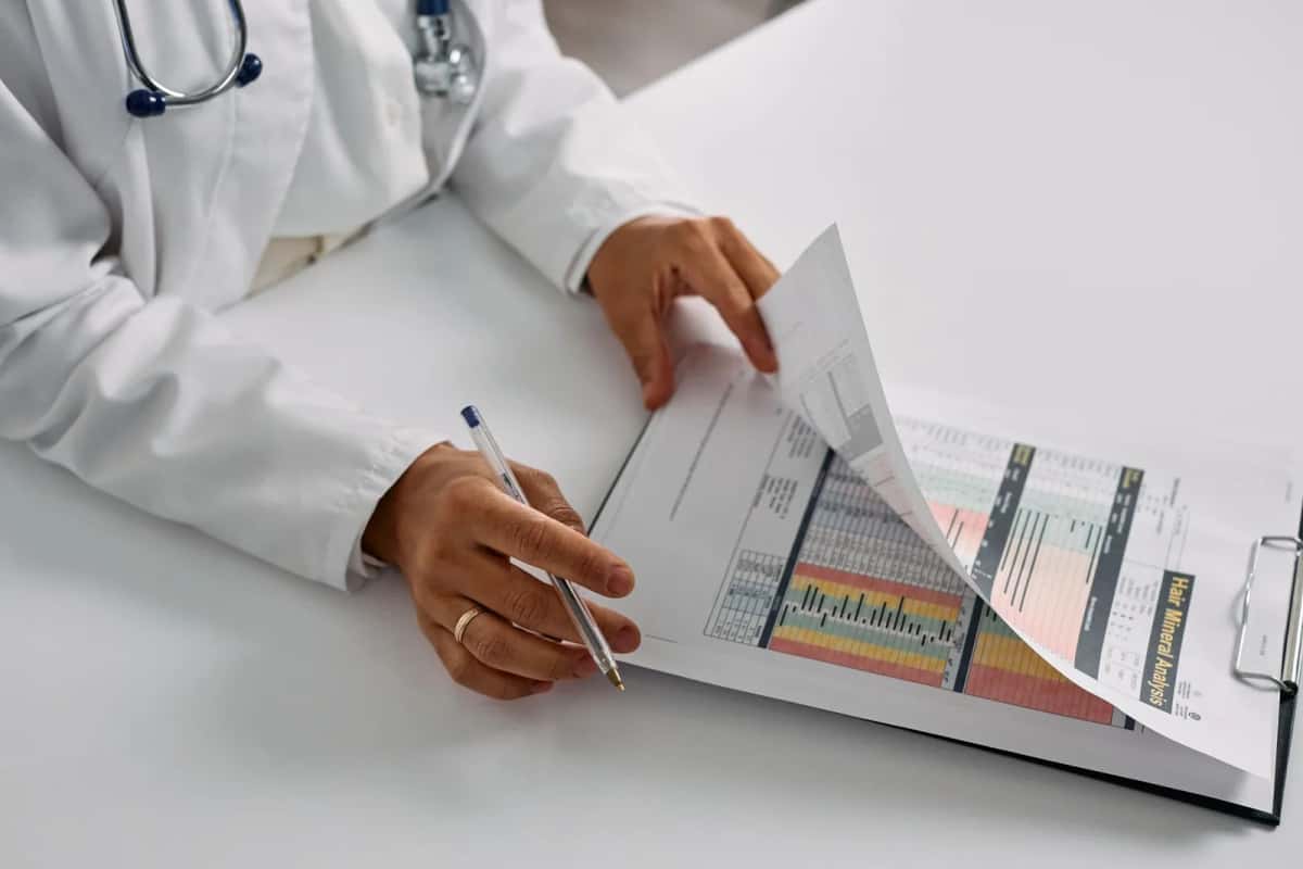 Médecin en blouse blanche examinant des documents de santé avec un stylo