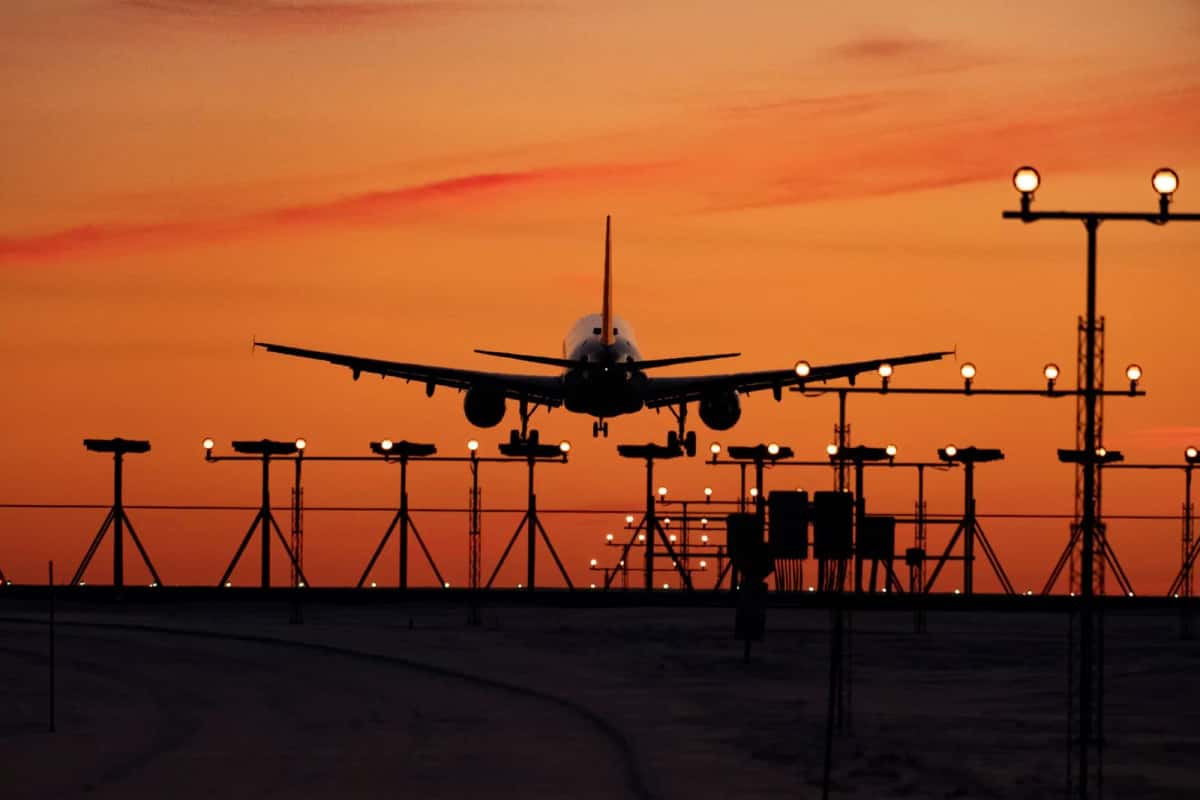 Avion à l'atterrissage sur une piste d'aéroport au coucher du soleil