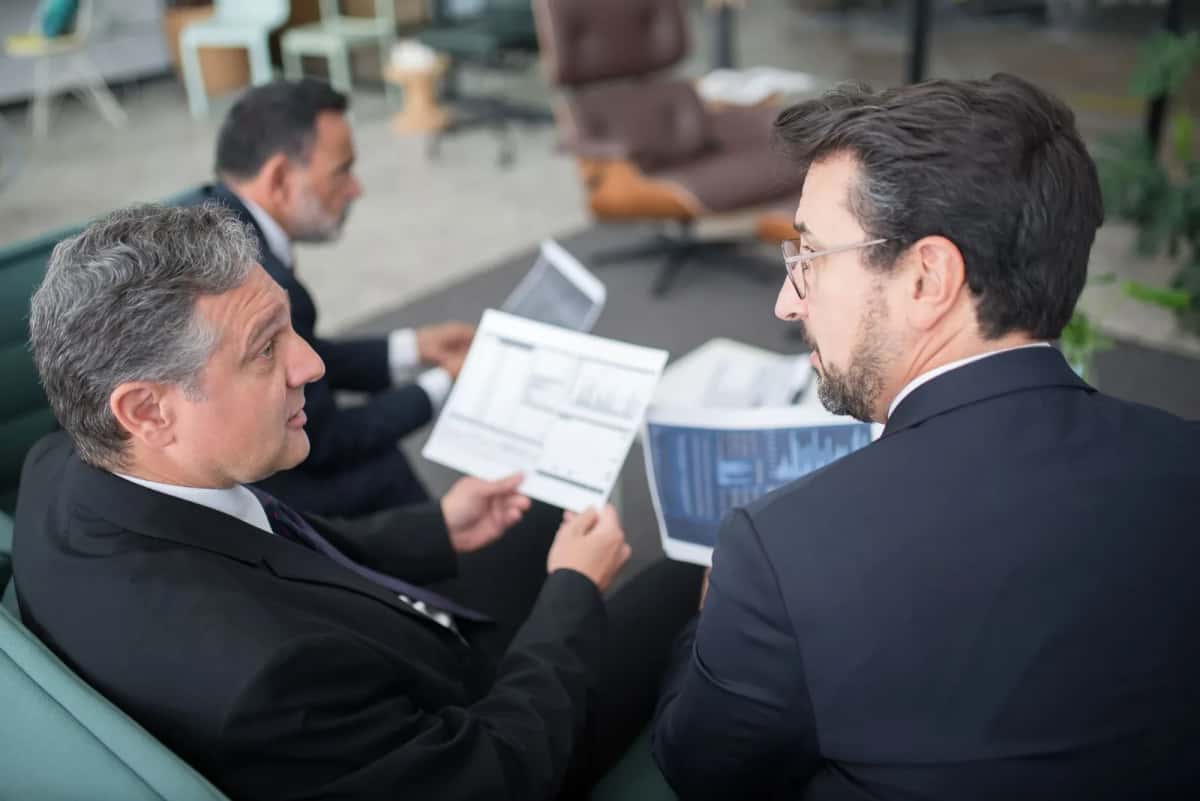 Deux cadres expatriés en costume comparent des tableaux financiers dans un bureau