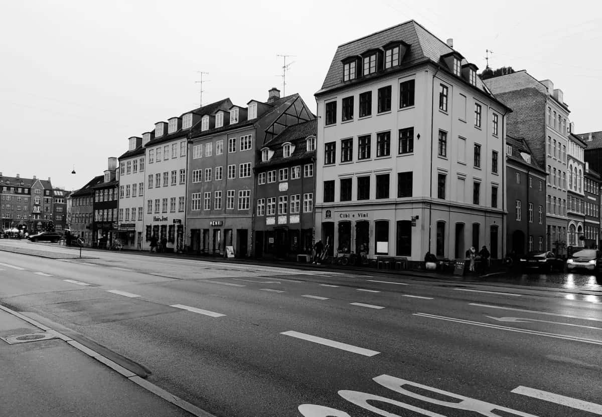 Carrefour désert en noir et blanc, immeubles anciens à l'angle et marquages de piste cyclable sur la chaussée