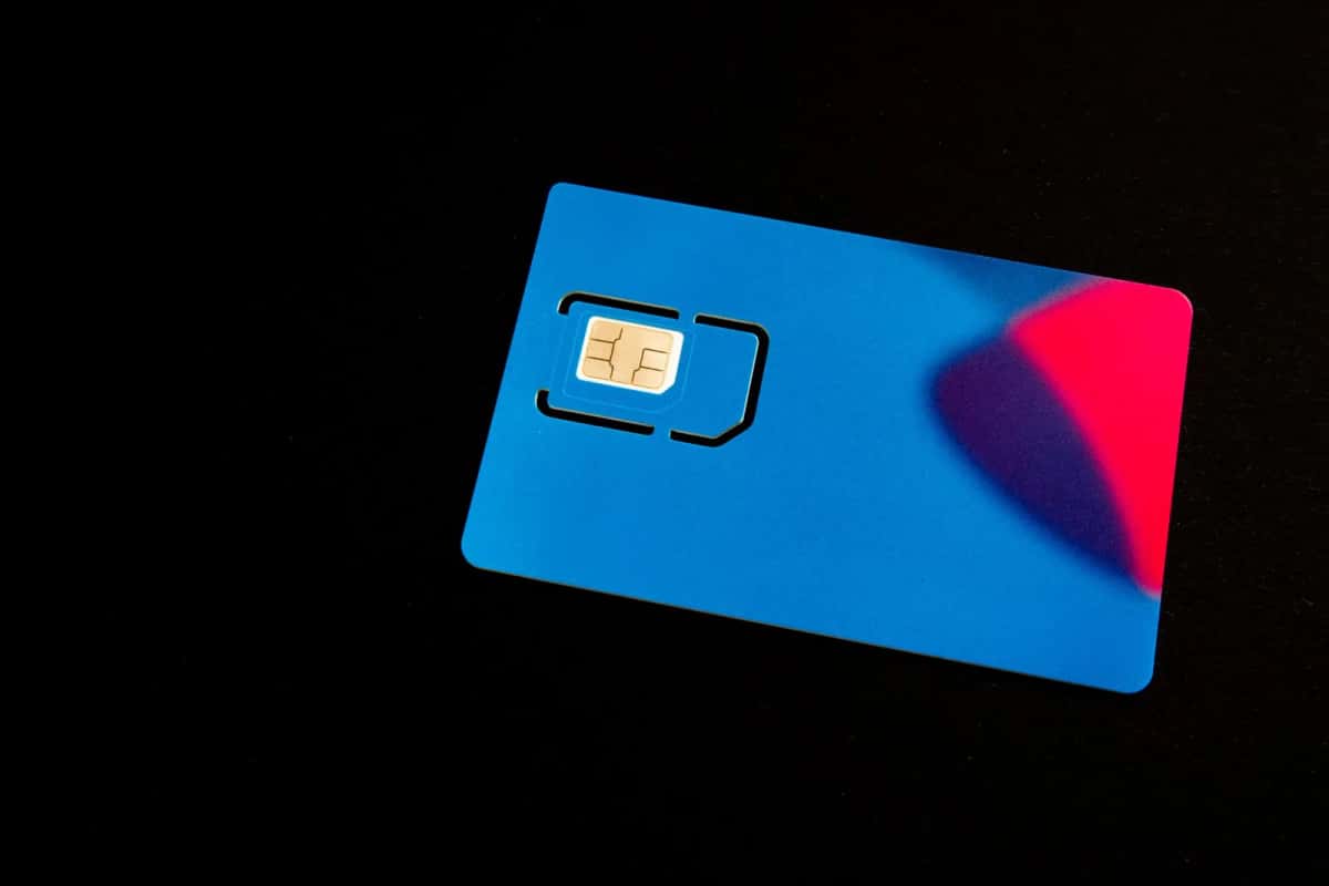 Carte SIM physique bleue posée sur un fond noir, sa puce dorée bien visible