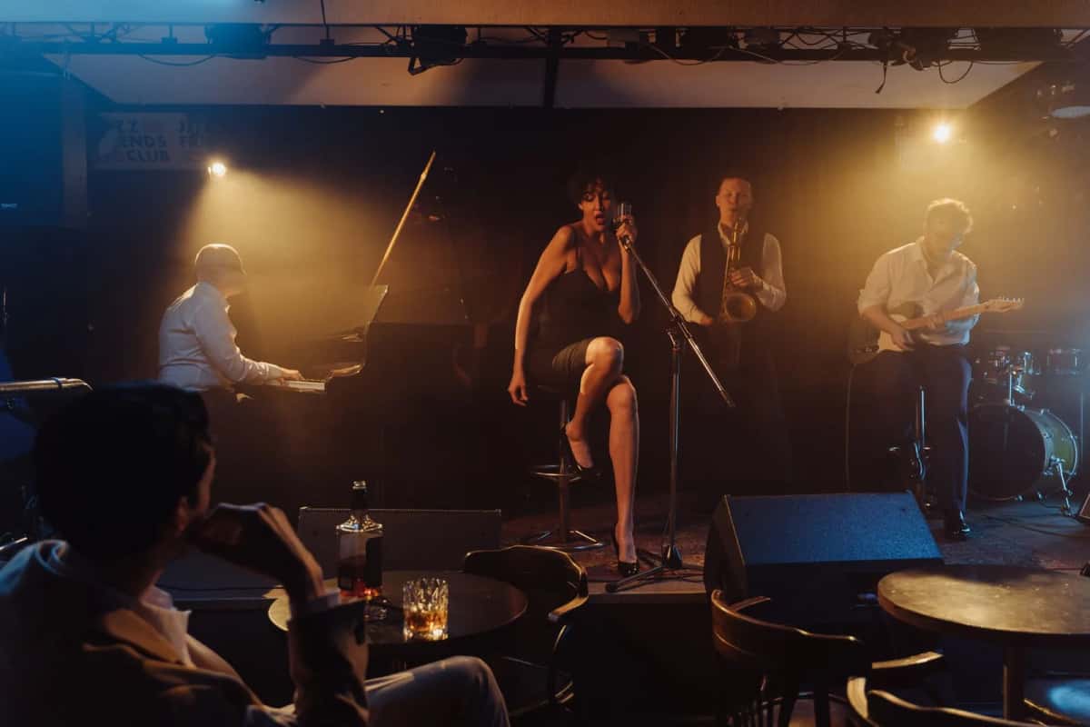 Quintet de jazz sur la petite scène d'un club, piano, contrebasse et chanteuse, devant un public assis à des tables