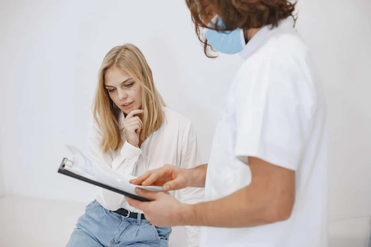 Consultation médicale entre une patiente et une médecin tenant un dossier de santé