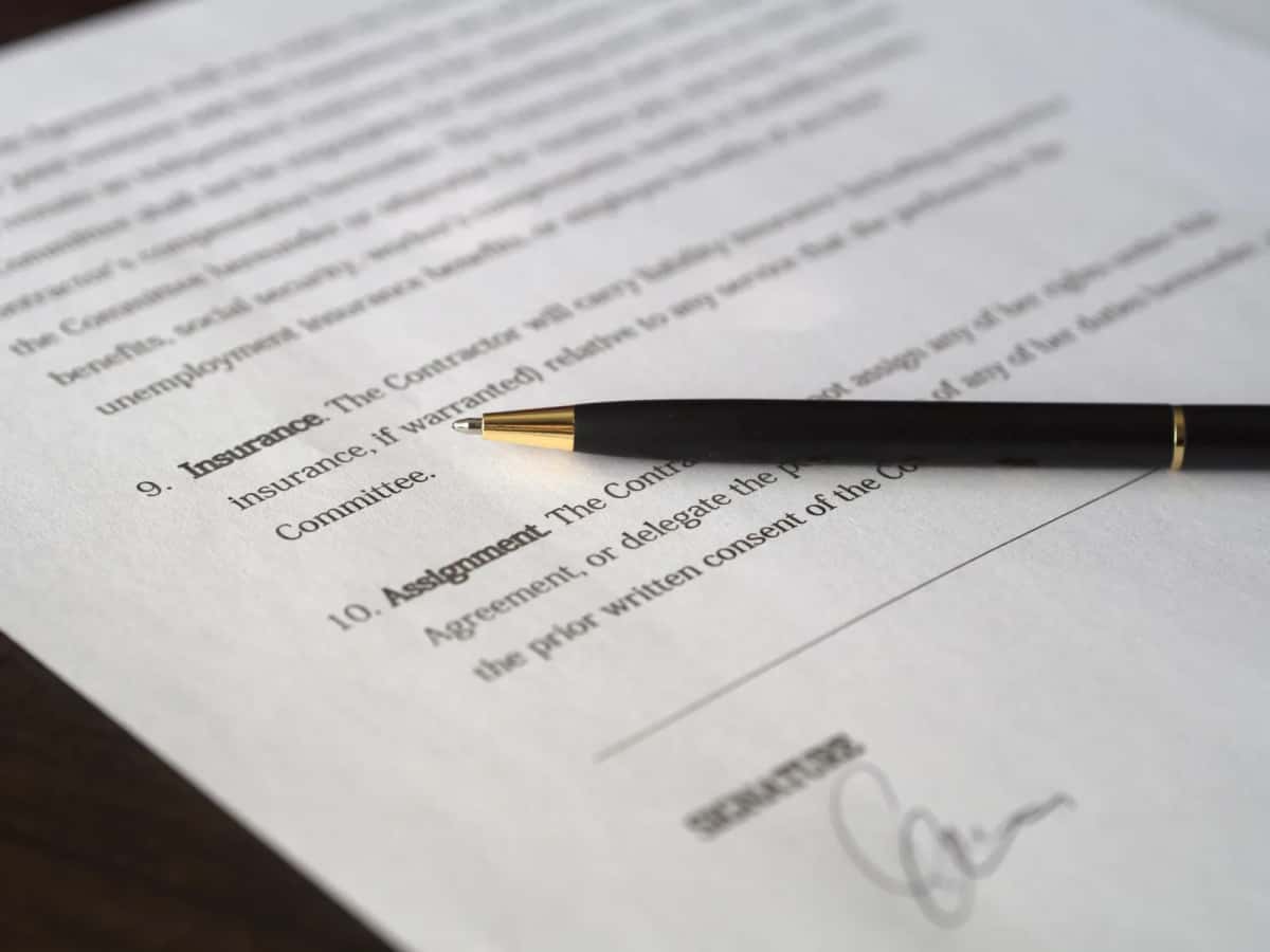 Gros plan sur un contrat d'assurance ouvert à la clause « Insurance », un stylo posé en travers de la page