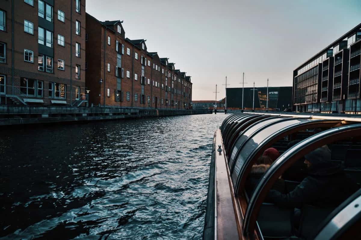 Bateau de promenade couvert glissant sur un canal bordé d'entrepôts de brique, à Copenhague