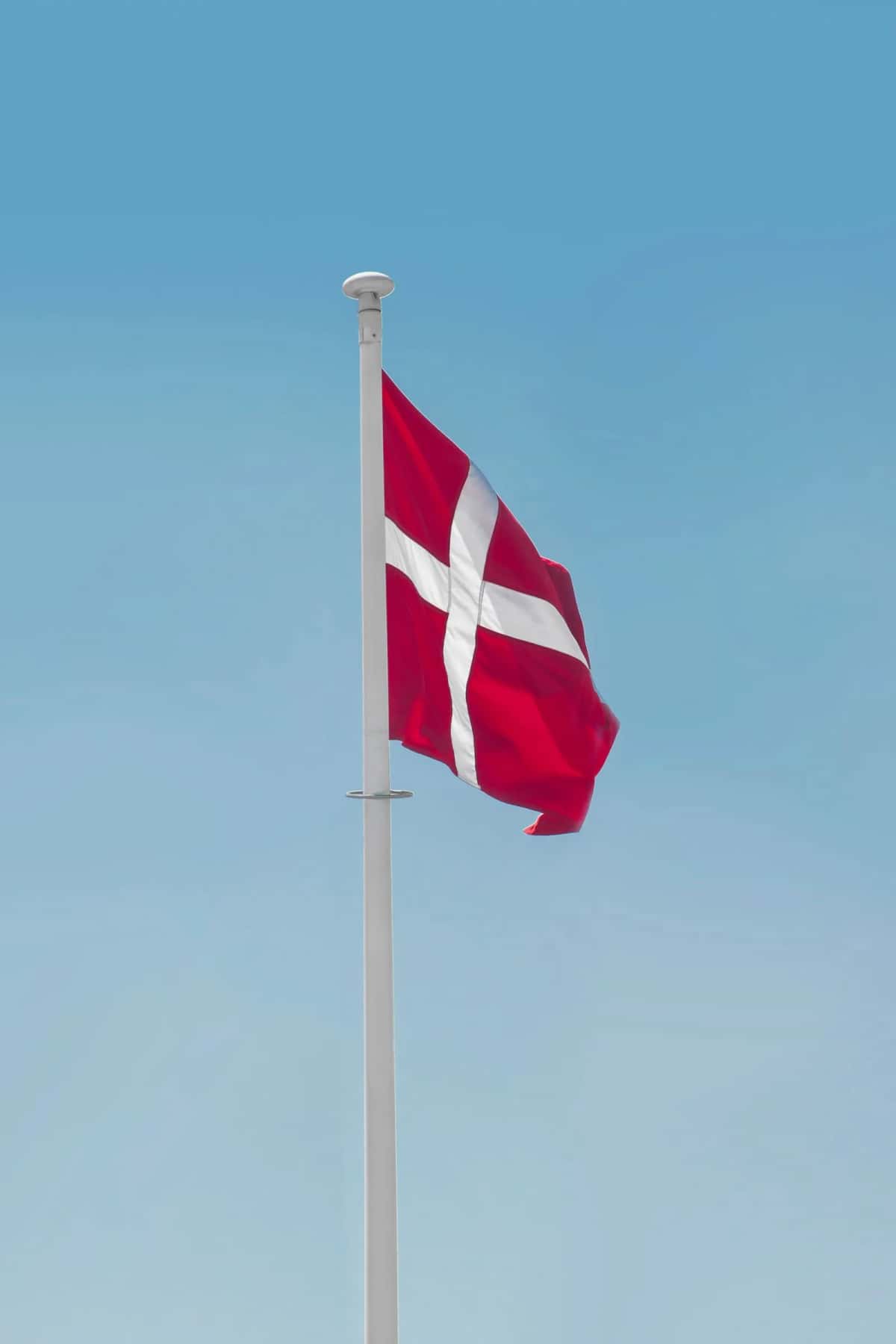 Le Dannebrog, drapeau danois, flottant sur un mât contre un ciel bleu