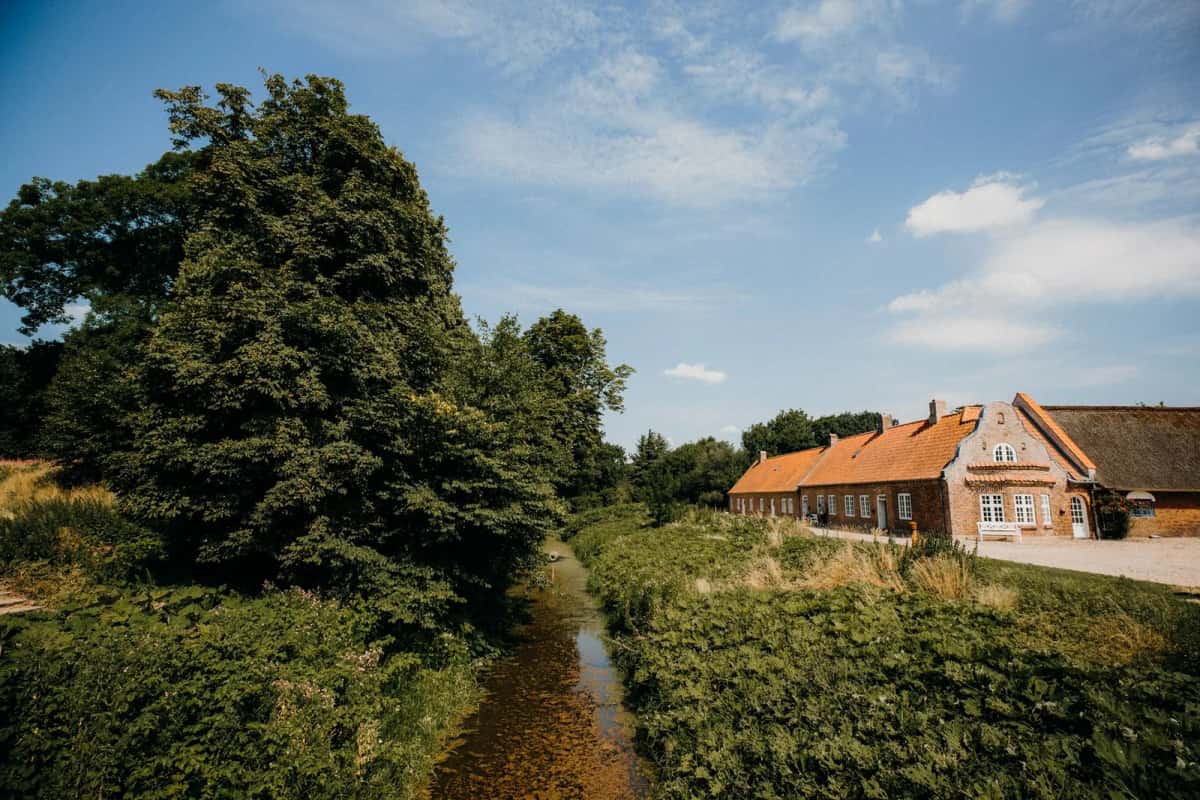 Ferme danoise traditionnelle en briques rouges au bord d'un ruisseau, dans la campagne verdoyante du sud du Danemark