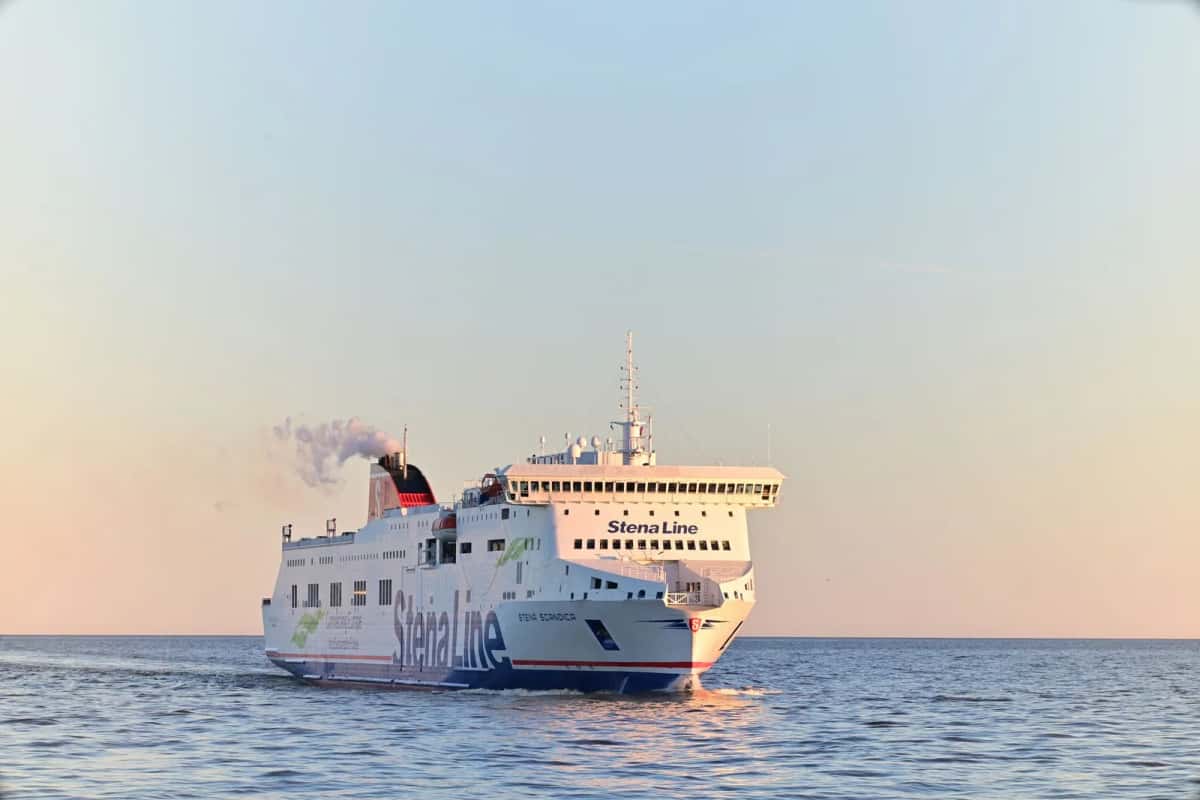 Un ferry Stena Line naviguant sur une mer calme au coucher du soleil, fumée blanche s'échappant de sa cheminée