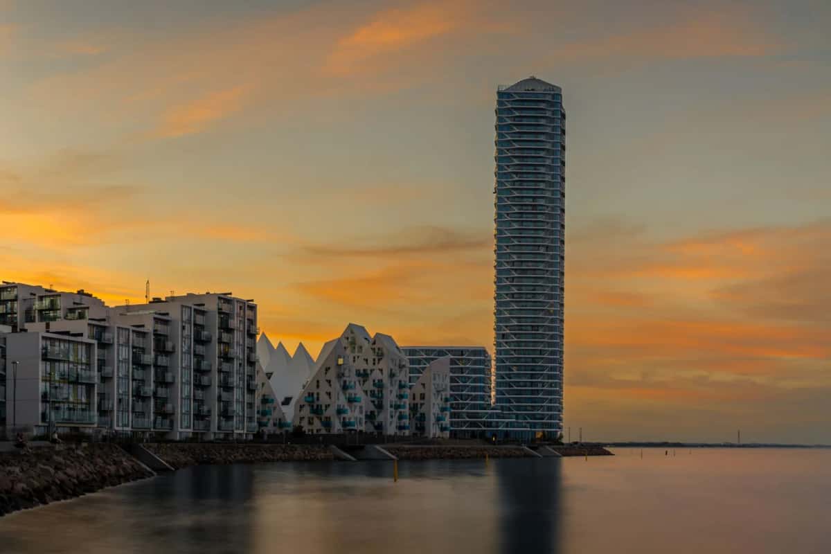 Front de mer d'Aarhus au crépuscule, immeubles blancs aux toits en pointes de banquise et haute tour vitrée au bord de l'eau