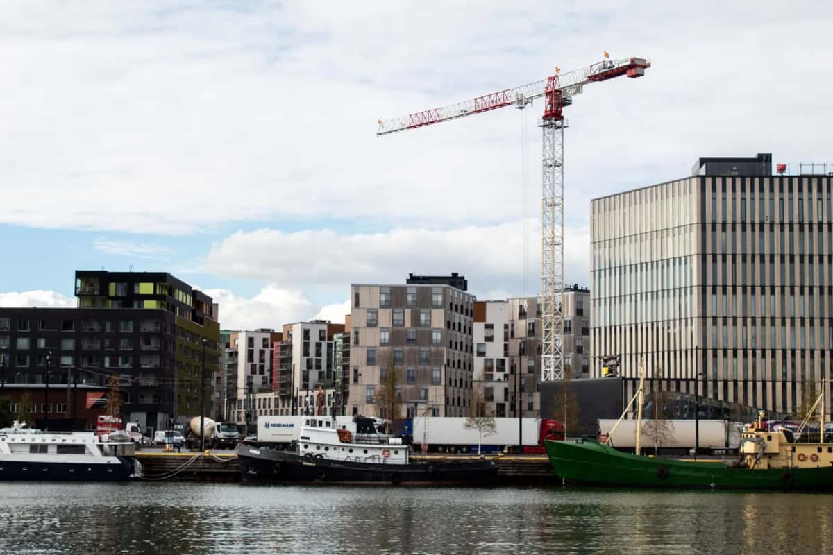 Front d'eau en travaux : immeubles de logements récents, une grue de chantier au-dessus des toits et des bateaux amarrés au premier plan