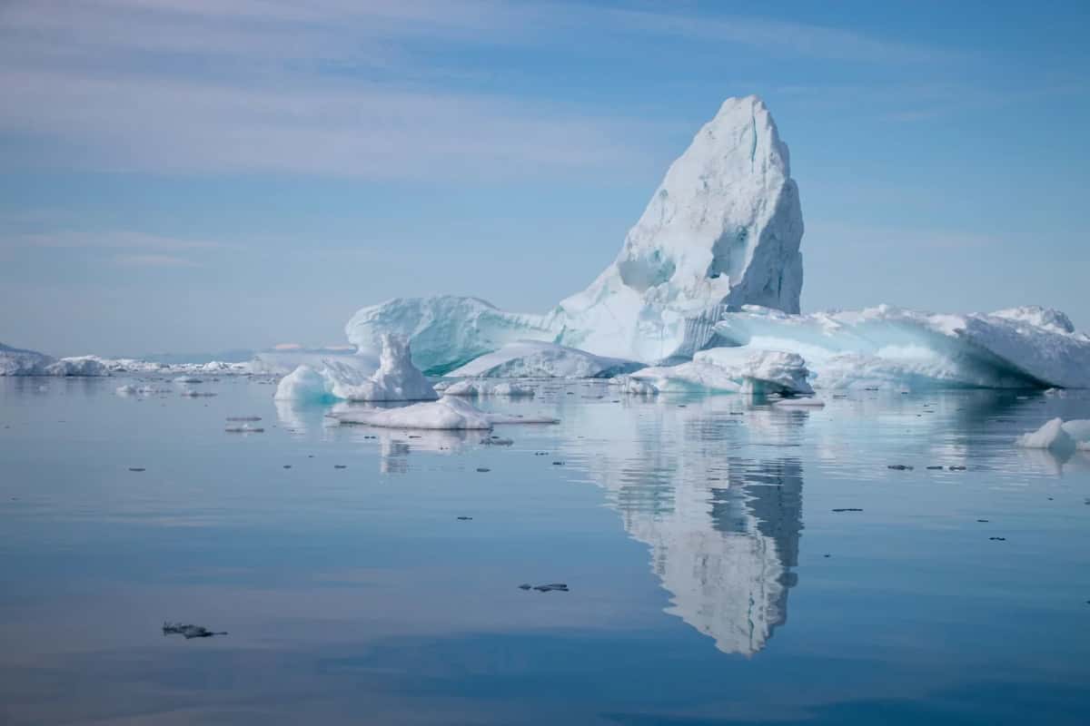 Iceberg géant se reflétant dans les eaux calmes de l'Icefjord d'Ilulissat, au Groenland