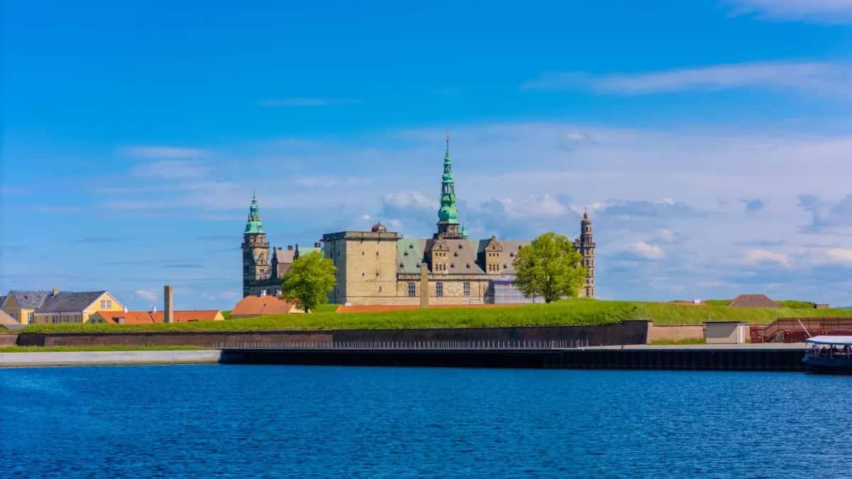 Le château de Kronborg à Helsingør vu depuis l'eau du détroit de l'Øresund, remparts gazonnés, tours à bulbe de cuivre vert et façades de grès
