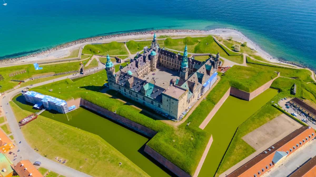 Vue aérienne de Kronborg : le château au centre d'un rempart en étoile entouré de douves et de talus herbeux, au bord du détroit