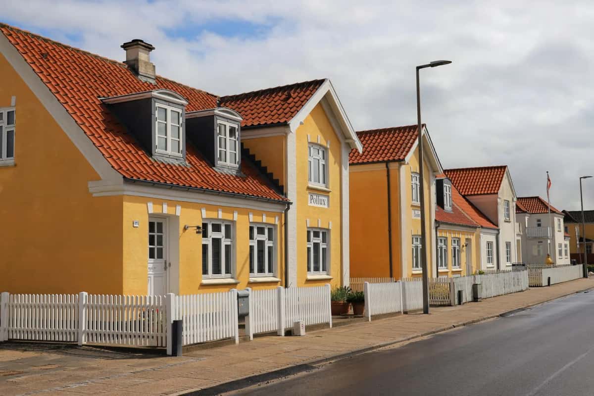 Rangée de maisons danoises jaunes à toit rouge et clôtures blanches à Løkken, Danemark