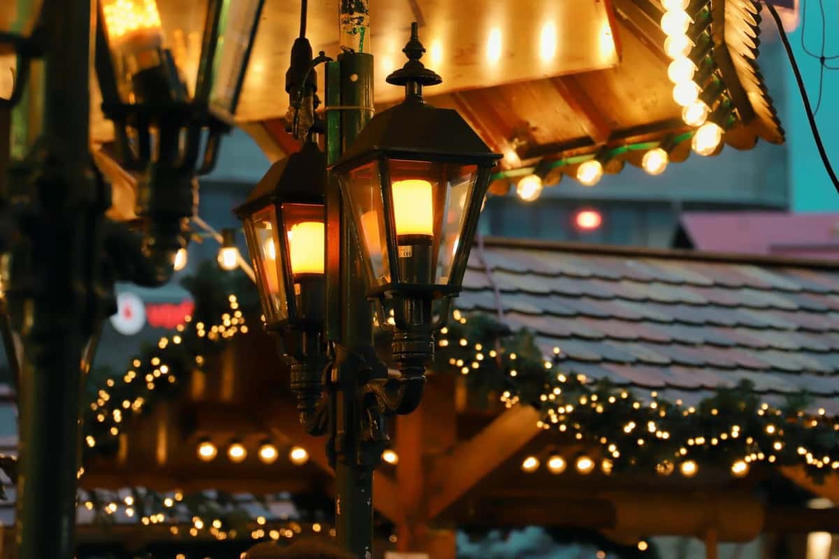 Chalets de marché de Noël sous des guirlandes lumineuses et de vieilles lanternes, à la tombée du jour