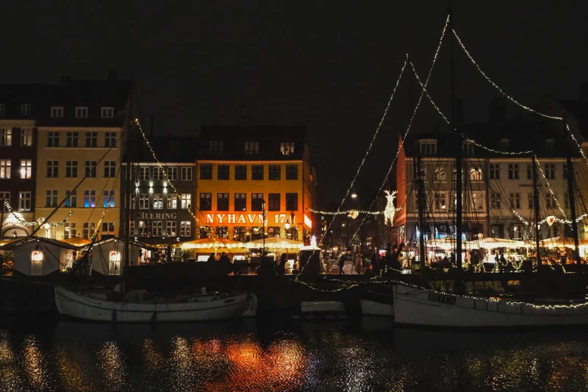 Nyhavn illuminé de nuit, bateaux amarrés devant les façades de Copenhague