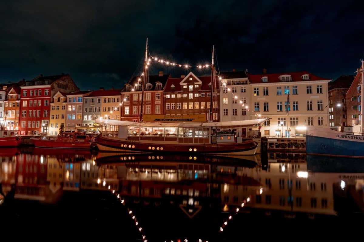 Nyhavn de nuit, guirlandes lumineuses tendues entre les mâts d'un bateau-restaurant et reflets des façades dans le canal