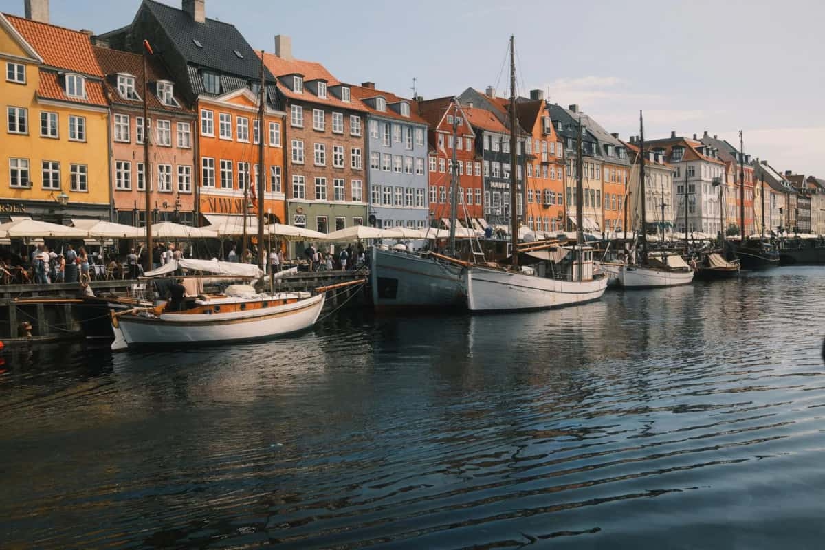Terrasses sous parasols blancs alignées le long du quai de Nyhavn, remplies en plein été