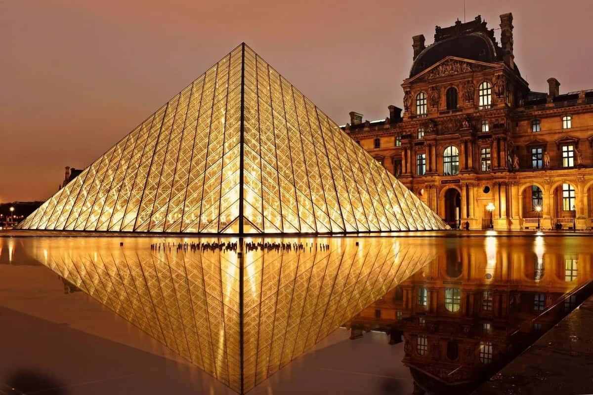 La pyramide du Louvre illuminée la nuit et se reflétant dans le bassin, devant l'aile Richelieu à Paris