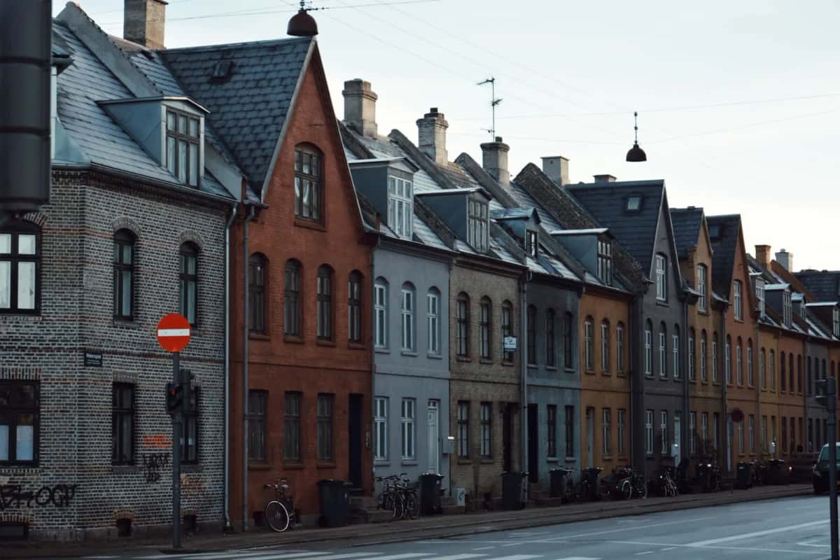 Rangée continue de maisons à pignon aux façades brique et crépi, vélos garés contre les murs le long du trottoir