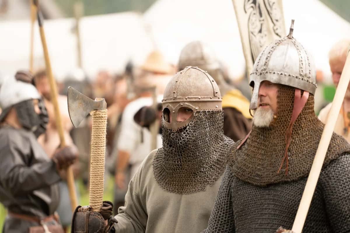 Figurants en cotte de mailles lors d'une reconstitution viking, casques coniques à protège-nez et à ventaille de mailles, haches et lances tenues à l'épaule