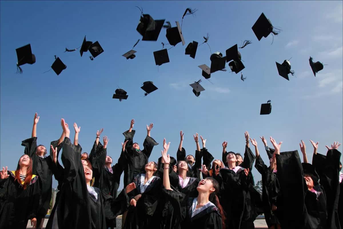 Des diplômés en toge lançant leurs toques en l'air à la fin d'une cérémonie de remise de diplômes
