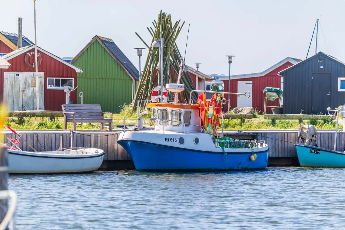 Petits bateaux de pêche immatriculés RI amarrés au port de Ringkøbing, cabanes de bois rouges et vertes alignées sur le quai