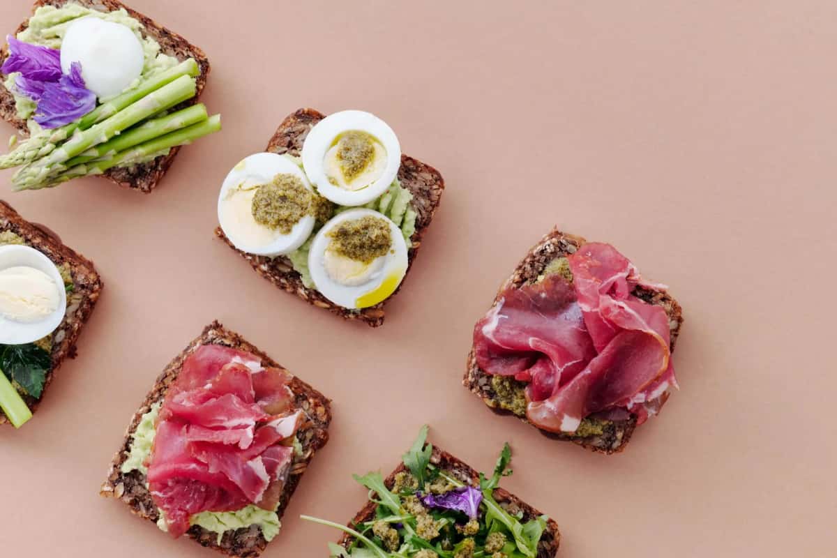 Tartines de pain de seigle garnies d'œuf, d'asperges, de rosbif et de fleurs comestibles, vues de dessus
