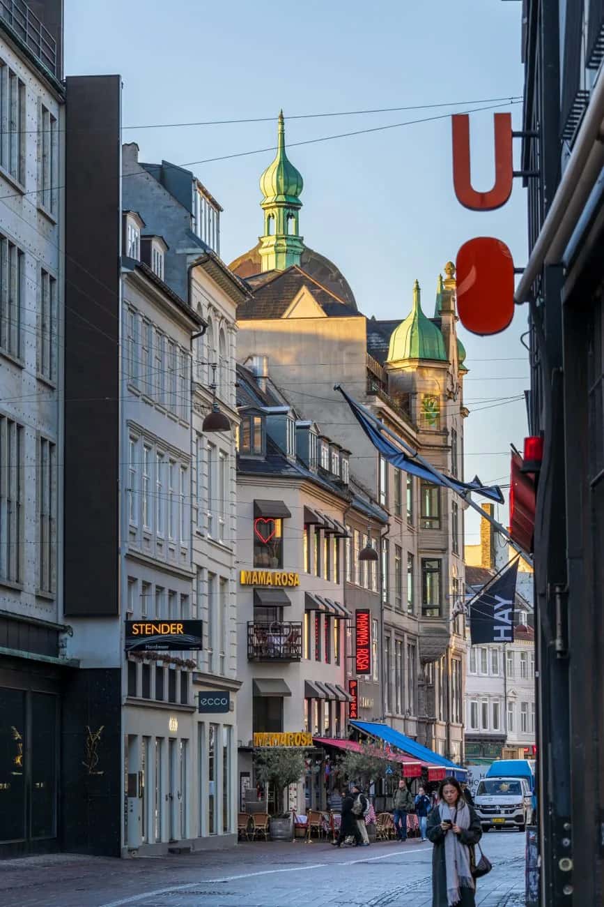 La rue piétonne Strøget à Copenhague, ses boutiques, ses cafés et les clochers verts en cuivre au bout de la rue