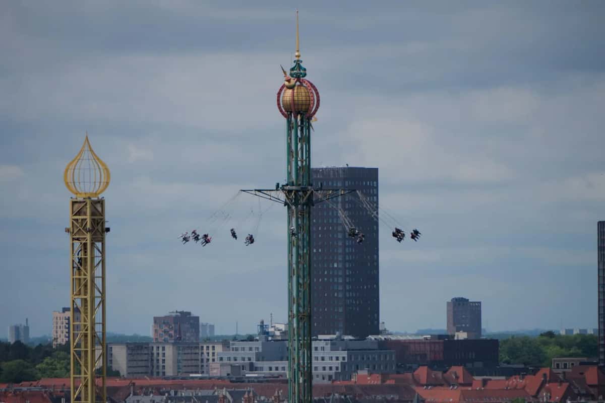 Le carrousel volant Himmelskibet en rotation au sommet de son mât, et la tour dorée du Golden Tower, au-dessus des toits de Copenhague